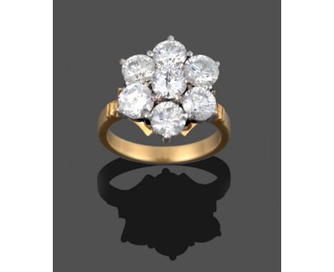 A Diamond Cluster Ring, seven round brilliant cut diamonds in white claw settings, to a yellow tapered shoulder plain polishe