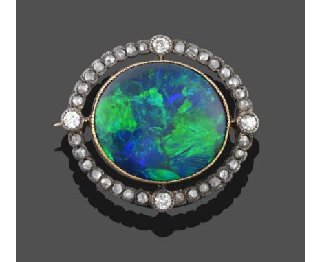 An Opal and Diamond Brooch, circa 1910, an oval polished black opal in a yellow millegrain setting, within a frame of rose cu