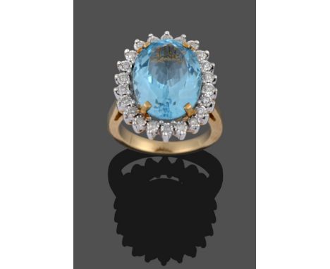 A 9 Carat Gold Blue Topaz and Diamond Cluster Ring, an oval cut topaz in a yellow four claw setting, within a border of round