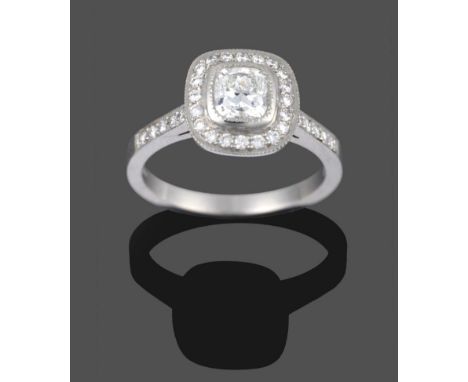 A Platinum Diamond Cluster Ring, a radiant cut diamond in a rubbed over setting, within a border of round brilliant cut diamo