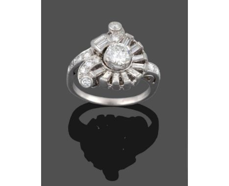 A Diamond Cluster Ring, a round brilliant cut diamond within an asymmetric spray comprised of baguette cut diamonds and round