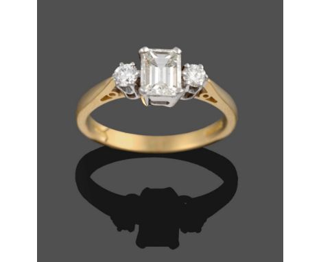 An 18 Carat Gold Diamond Three Stone Ring, an emerald-cut diamond sits between two round brilliant cut diamonds, in white cla