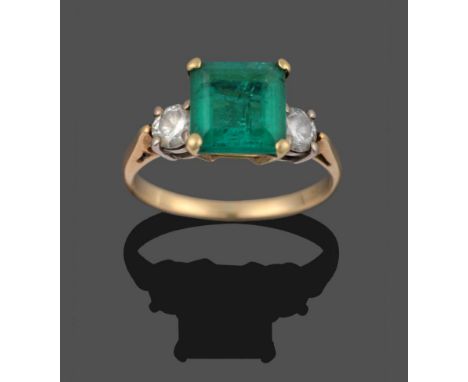 An Emerald and Diamond Three Stone Ring, the emerald-cut emerald flanked by two round brilliant cut diamonds in yellow claw s