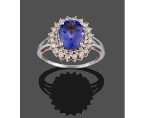 An 18 Carat White Gold Tanzanite and Diamond Ring, the oval cut tanzanite within a border of round brilliant cut diamonds and