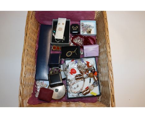 A wicker basket containing various costume jewellery including dress ring, 925 silver and amber set brooch, a pair of similar