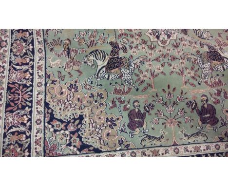 TURKISH BORDERED RUG OF KIRMAN HUNTING STYLE decorated in traditional style, on a green ground, 244cm x 158cm 