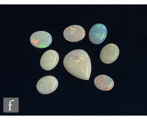 Eight cut and polished loose unused opal stones, seven oval cabochon cut, lengths approximately 10mm, with a similar pear sha