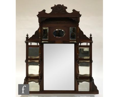 A late 19th Century walnut overmantel mirror, the central rectangular mirror panel flanked by nine smaller mirror panels, bra