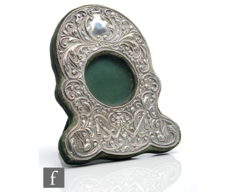An Edwardian hallmarked silver easel photograph frame with central circular window within a foliate scroll shaped border deta