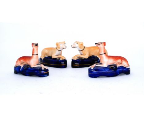 GREYHOUNDS: Two pairs of Staffordshire Pottery Quill Stands, modelled as seated Greyhounds, mid 19th century,  a pair with at
