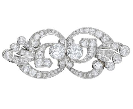An Art Deco diamond brooch, of open scrollwork design, centrally set with two old brilliant-cut diamonds within a surround of