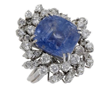 A sapphire and diamond dress ring, of whorl design, the cushion-shaped sapphire in a stepped surround of brilliant-cut diamon