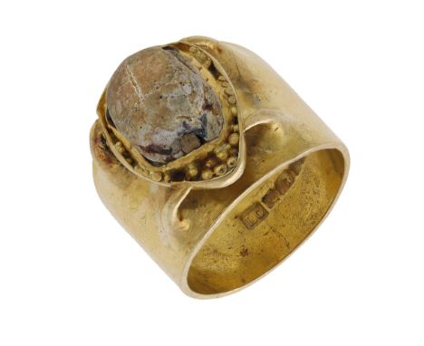 An 18ct gold scarab set ring by Louis Osman, 1976, the antique scarab set within a granulated mount, later applied to a broad