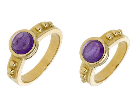 A pair of amethyst rings, each set with a circular amethyst cabochon between shoulders with beaded decoration, stamped ‘750’,