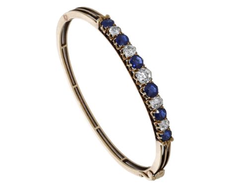 A late 19th century sapphire and diamond bangle, set with an alternating row of circular-cut sapphires and old brilliant-cut 