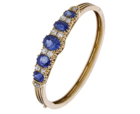 A late 19th century sapphire and diamond hinged bangle, the pierced bangle set to the front with three graduated oval mixed-c