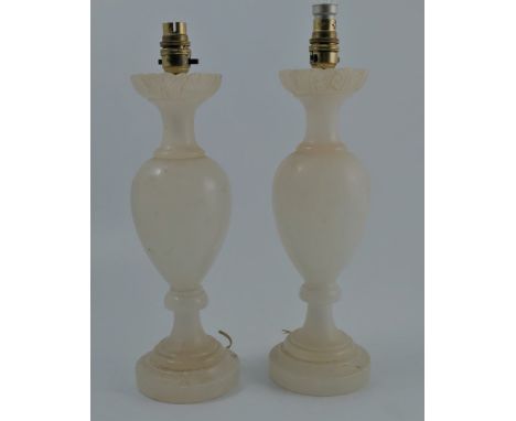 A near pair of alabaster lamp bases, with carved leaves to the top rim, baluster column raised on a stepped circular foot, he