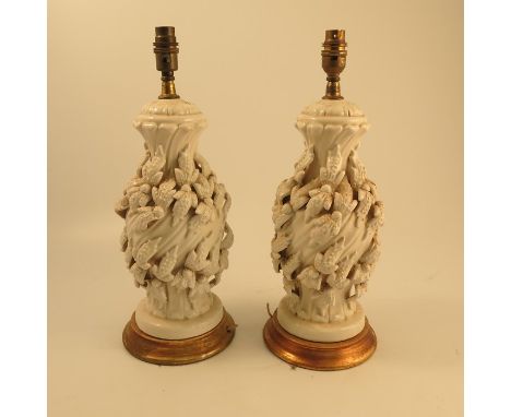 A pair of white pottery lamp bases, of baluster form, the wrythen moulded ground decorated with leaves, on a gilt wooden base