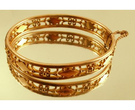 A hinged bangle, stamped '15ct', of open work design, 1cm wide, internal diameter 6cm, 15g gross