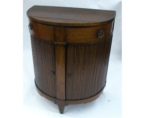 An antique oak D shaped cabinet, fitted with two frieze drawers over two tambour cupboards, opening to reveal a fitted shelf,