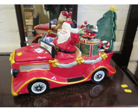 A ceramic model of Father Christmas in a car filled with toys, the car forming a lidded box, the presents forming two lidded 