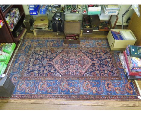 A Persian rug, with red medallion on a blue field with herati and flowerheads within a light blue border 192cm x 130cm