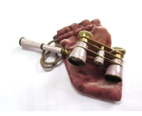 A pair of opera glasses with holding handle, the glasses decorated in pink enamel over engine turning