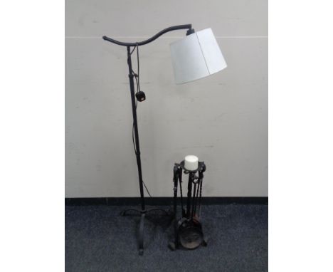 A contemporary metal floor lamp on tripod support together with a wrought iron companion set/ candlestick  