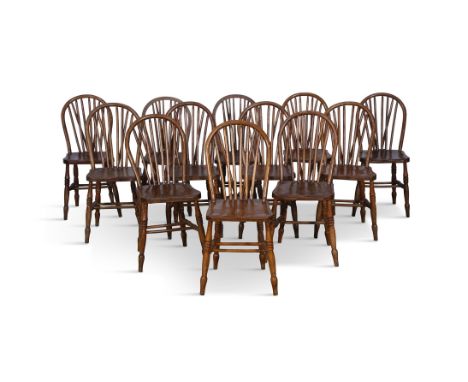 A SET OF TWELVE 19TH CENTURY STAINED TIMBER CURVED RAILBACK CHAIRS,the stick backs and dished saddle seats on splayed turned 