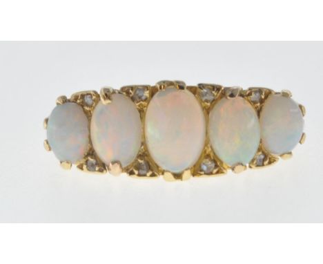 A vintage hallmarked 18ct gold five stone ring set with five oval opal cabochons with diamond accent stones and set within a 