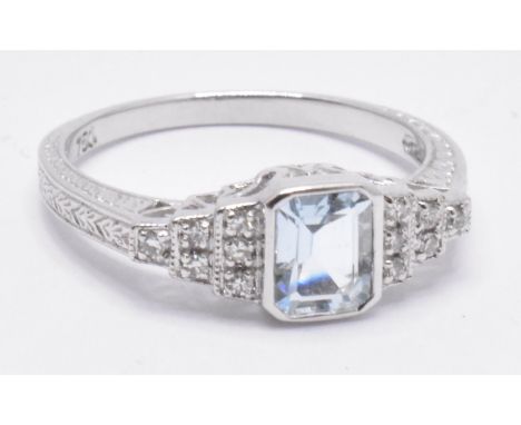 An 18ct white gold aquamarine and diamond Art Deco ring. The ring with central emerald cut aquamarine on stepped diamond shou