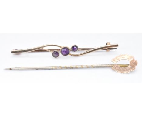 A 9ct gold and amethyst brooch pin together with a stick pin having a 9ct gold horseshoe motif. Both marked 9ct, tests indica