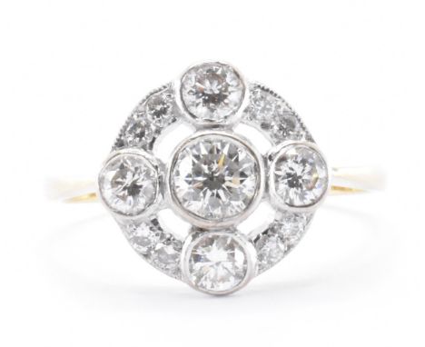 A 1930's Art Deco 18ct gold and diamond cluster ring. The ring set with a central round brilliant cut diamond with a quatrefo