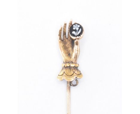 A 19th Century George III gold stick pin having a finial in the form of a hand holding a carved black and white agate flower 