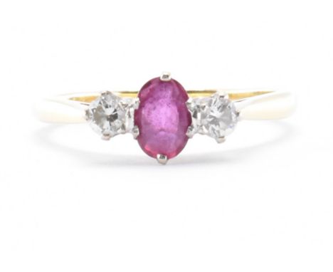 A hallmarked 18ct gold diamond and ruby three stone ring. The ring being set with an oval cut ruby flanked by two round cut d