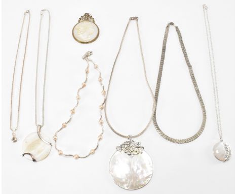 An assortment of silver pendant necklaces and chains to include a mother of pearl pendant necklace, a mother of pearl carved 