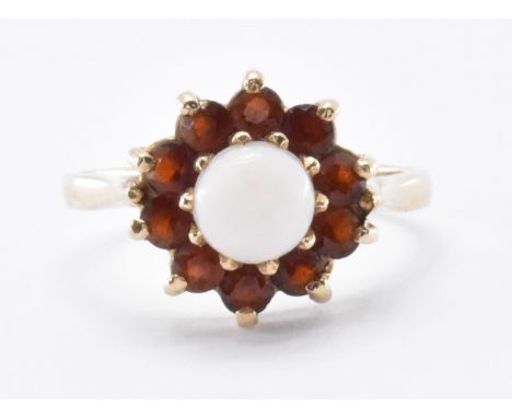 A hallmarked 9ct gold opal and garnet&nbsp; ring. The ring having a central opal cabochon within a claw settings surrounded b