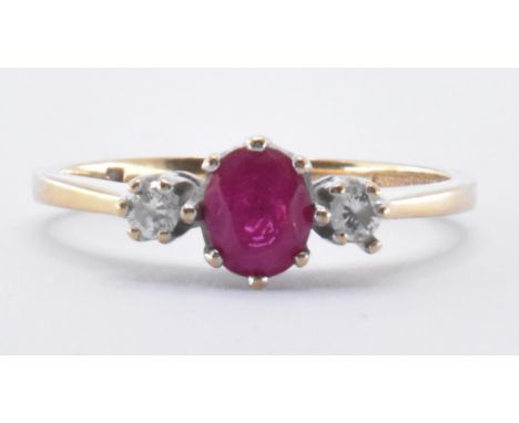 A hallmarked 9ct gold synthetic ruby and diamond three stone ring. The ring set with a central oval cut synthetic ruby flanke