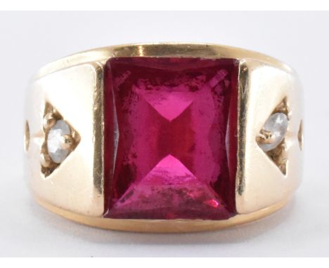 A 14ct gold and synthetic ruby ring being set with a large rectangular cut synthetic ruby, flanked by two round cut white sto