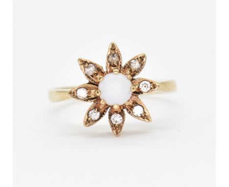 A hallmarked 9ct gold opal and diamond ring. The ring having a round opal cabochon within a flower head with eight diamond ac