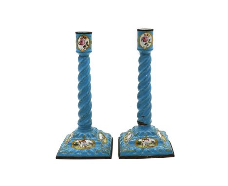 A pair of enamel candlesticks,19th century, possibly Staffordshire, the spiral columns on square bases, decorated with figura