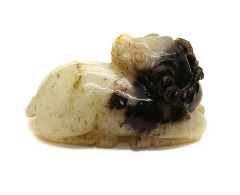 A Chinese jade carving,20th century, of a recumbent buffalo turning its head to the back, the stone of white and black tone,6