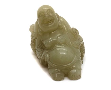 A Chinese jade carving,20th century, of Budai seated wearing a long robe exposing his bare belly, surrounded by two boys,6.5c