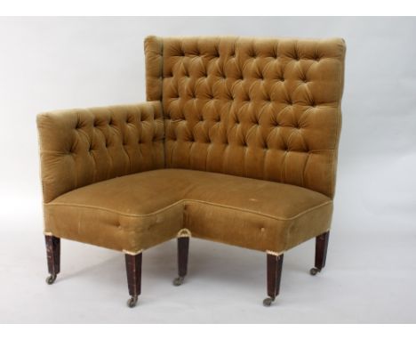 An unusual Edwardian corner sofa, button upholstered in gold material, on square tapered legs and brass castors