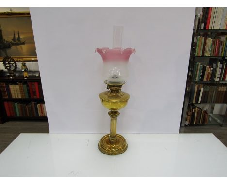 A brass Edwardian oil lamp with etched cranberry shade