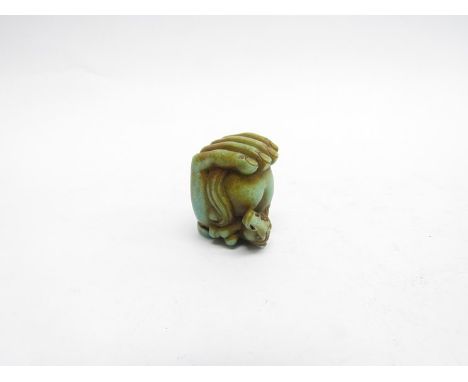 A jade netsuke horse in hand 