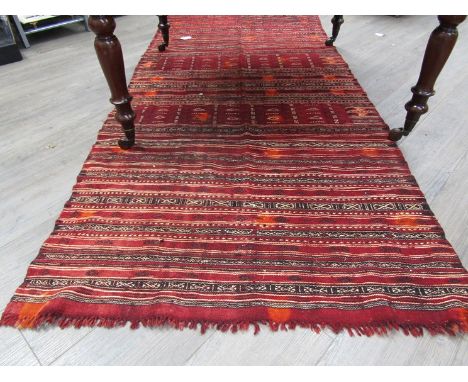 A nomadic tribal striped wool carpet worked in madder, browns and cream. 250cm x 115cm. Badly stained