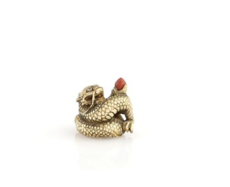 A small stained ivory netsuke of a coiled dragon, holding a tama, 19th or 20th CenturyProvenance: The Property of a Lady. Fro