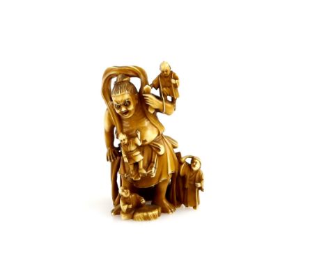A small stained ivory okimono carved as pilgrims clambering over a large Temple Nio, 5.5 cm high, 19th or 20th CenturyProvena