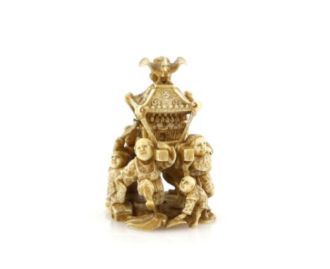 An okimono style netsuke with single himotoshi, carved as a crowd of boys carrying a large Shinto or Buddhist shrine, 5cm wid